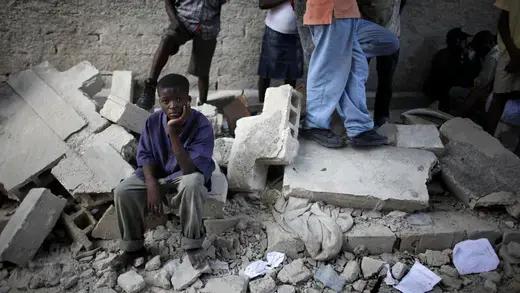 A boy in Haiti sits next to the remains of a destroyed school after an earthquake.