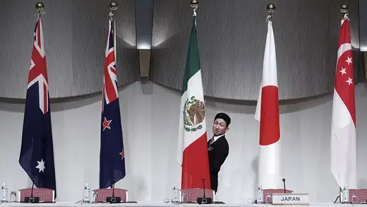A staff adjusts the Mexican flag prior to joint press conference for CPTPP  in Tokyo.